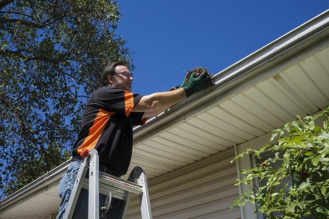 a handyman adjusting a gutter to direct rainwater away from a building in Anderson IN